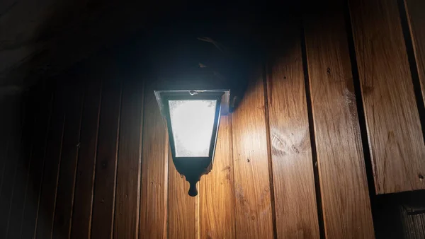 晚上在木制墙壁的后面点亮路灯 光线弥漫在黑暗中 创造一个舒适的 案文的篇幅 — 图库照片