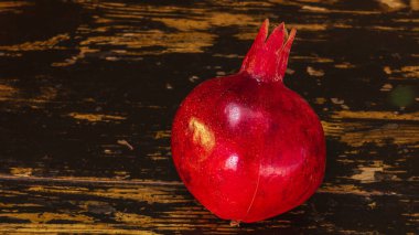 Masanın üzerinde kırmızı nar yatıyordu. Masanın üzerinde siyah ve beyaz ahşap bir arka plan var. Hayat konsepti.