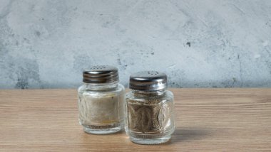 Modern tuz ve klasik biber öğütücüleri ahşap dokuma masasında duruyor. Tahta tahtada tuzluk ve biberlik. Metin için boşluk.