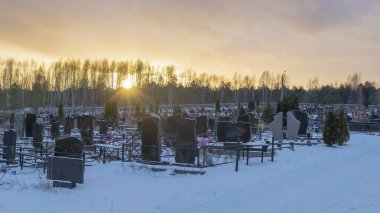 Karanlık mezar taşları ve ağaçlarla kaplı bir mezarlığın üzerinde kış günbatımı. Ölümden sonra. Samsara kavramları. Ölülerin dirileceği umudu. Metin için boşluk.