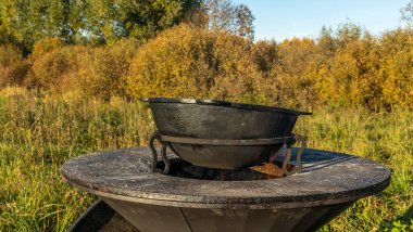 Açık havada sokak yemekleri pişen büyük bir tencere. Mutfak açık havada. Ateşte metal kazan var. Rahat bir yaşam tarzı..