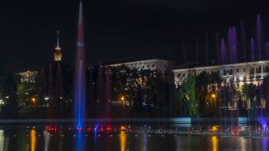 Geceleyin bir nehirde çok renkli bir müzik çeşmesi. Aydınlanmadan kaynaklanan gece çeşmesi. Mesaj için yer var. Kutlama konsepti.