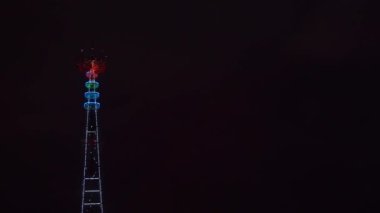 Minsk 'teki aydınlanmış TV yayın kulesinin panoramik görüntüsü. Minsk 'teki TV Kulesi' nin gece manzarası. Şenlik ve teknoloji kavramları. 4k video.