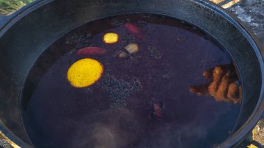 Sıcak sıcak şaraplı kazanlar. Sıcak şarap sokaktaki eski bir kazanda pişirilir. Açık ateşte yemek pişirmek. Yakın plan. Neşeli alkol içeceği..