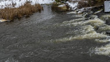 Bir yaya köprüsünün altındaki kış nehrinde kaynar su. Soyut arkaplan. Mesaj için yer var. Doğa kavramları.