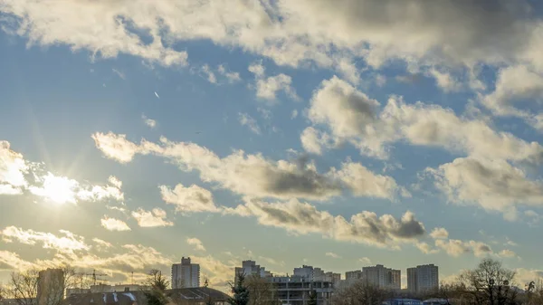 İlk kar şehirdeki yerleşim yerlerini kaplıyor. Güneş ışığı ve bulutlu gökyüzü. Şehir kavramları. Arka planda yüksek binalar var..