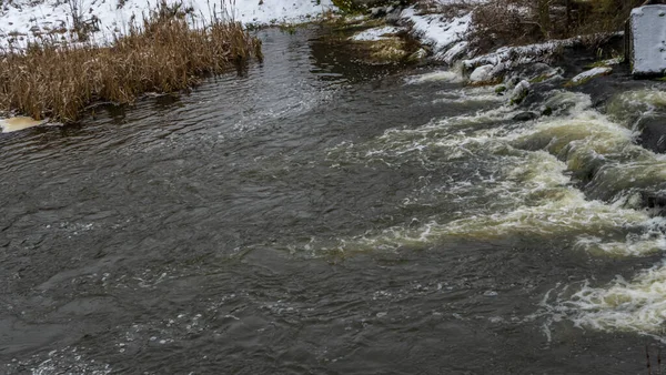 Bir yaya köprüsünün altındaki kış nehrinde kaynar su. Soyut arkaplan. Mesaj için yer var. Doğa kavramları.