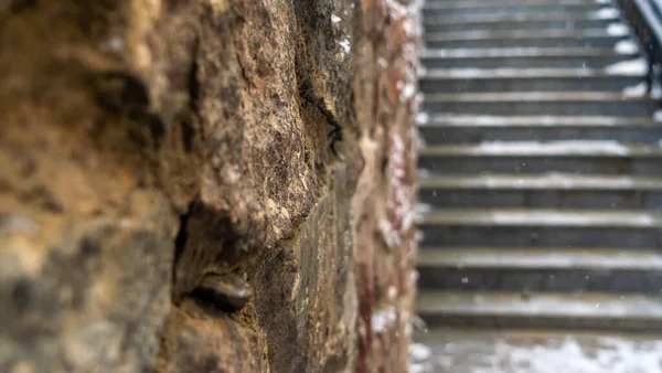 Kış havasında eski bir taş duvar. Arka plandaki merdivenlerde. Huysuz kavramlar. Doku ve arka plan. Mesaj için yer var. Uzayı kopyala Seçici odak.