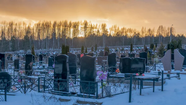 Karanlık mezar taşları ve ağaçlarla kaplı bir mezarlığın üzerinde kış günbatımı. Ölümden sonra. Samsara kavramları. Ölülerin dirileceği umudu. Metin için boşluk.