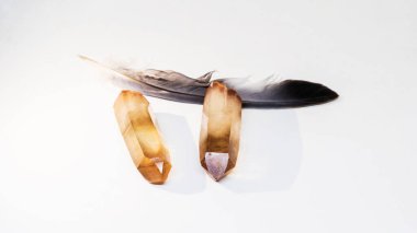 Çift Smokey Quartz Cilalı Kristaller Noktası ve kuş tüyü beyaz arka planda uzanır. Ayrı bir kavram.