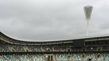Sahne ışıklarıyla direkler dramatik gökyüzü arka planında stadyumu aydınlatıyor. Metin için boşluk.