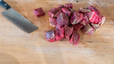 Doğranmış et ve bıçakla doğrama tahtasına yakın çekim. Pişirmek için çiğ et. Taze çiğ biftek şeritleri. Ev yapımı yemek pişirme konseptleri. Metin için boşluk.