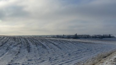 Arkasında ağaçlar olan kar altında kış tarım arazisi manzarası. Kırsalda karla kaplı kış manzarası. Metin için boşluk.