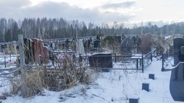 Mezarlıkta kar yağıyor. Kışın kar altında geleneksel mezarlık. Mezarlıkta mezar taşı var. Kışın karla kaplı bir mezarlık. Dramatik gökyüzü arkaplanı. Metin için boşluk.