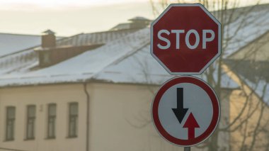 Yol işaretleri. Gelen trafiğin avantajı ve binanın arka planında Stop Road. Seçici odaklanma ve bokhe. Sokak işaretleri.