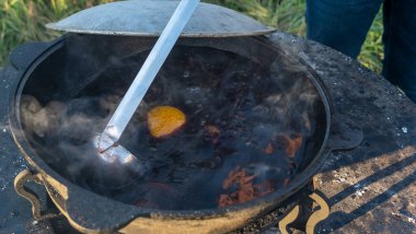 Sıcak sıcak şaraplı kazanlar. Sıcak şarap sokaktaki eski bir kazanda pişirilir. Açık ateşte yemek pişirmek. Yakın plan. Neşeli alkol içeceği..