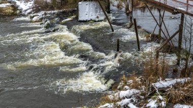 Bir yaya köprüsünün altındaki kış nehrinde kaynar su. Soyut arkaplan. Mesaj için yer var. Doğa kavramları.