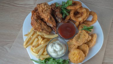 Atıştırmalık tabaklar - peynir çubukları, tavuk nugget, soğan halkaları, patates kızartması ve soslar. Bira tahtası. Yatay fotoğraf. Bar menüsü için fotoğraf.