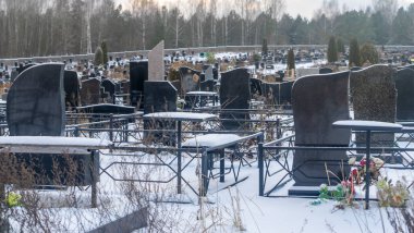 Mezarlıkta kar yağıyor. Kışın kar altında geleneksel mezarlık. Mezarlıkta mezar taşı var. Kışın karla kaplı bir mezarlık. Dramatik gökyüzü arkaplanı. Metin için boşluk.
