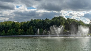 Çeşmeden su. Bulutlu gökyüzünün arkasındaki çeşme akıntısının tepesinde. Nehirdeki çeşme dramatik gökyüzüne karşı.
