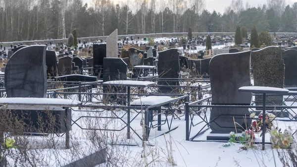 Mezarlıkta kar yağıyor. Kışın kar altında geleneksel mezarlık. Mezarlıkta mezar taşı var. Kışın karla kaplı bir mezarlık. Dramatik gökyüzü arkaplanı. Metin için boşluk.
