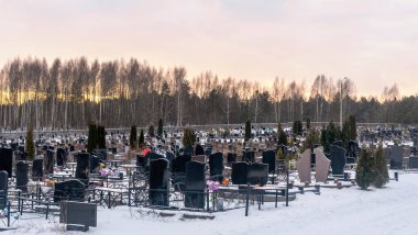 Karanlık mezar taşları ve ağaçlarla kaplı bir mezarlığın üzerinde kış günbatımı. Ölümden sonra. Samsara kavramları. Ölülerin dirileceği umudu. Metin için boşluk.