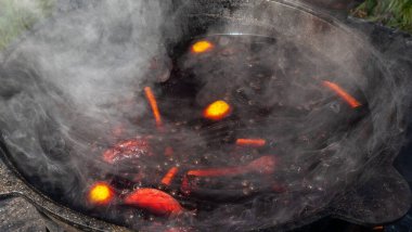 Sıcak sıcak şaraplı kazanlar. Sıcak şarap sokaktaki eski bir kazanda pişirilir. Açık ateşte yemek pişirmek. Yakın plan. Neşeli alkol içeceği..