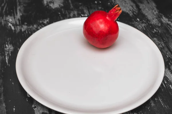 Ολόκληρο Κόκκινο Ρόδι Μεγάλο Άσπρο Πιάτο Μαύρο Και Άσπρο Ξύλινο — Φωτογραφία Αρχείου