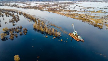 Dredger nehirdeki çim alanını derinleştirmeye çalışıyor. Nehirdeki bir tarakçı tarafından temizleniyor ve derinleşiyor. Nehirde gün batımı. Endüstriyel kavram.