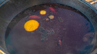 Büyük bir kazanda şarap kaynattım. Sıcak şarap büyük bir tencerede pişirilir. Geleneksel festivalde vitaminler. Çeşitli meyve ve baharatlarla sıcak şarap.