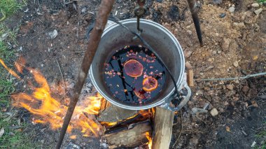 Sıcak kamp ateşinin üstünde, turist tenceresinde sıcak şarap. Ateşin yanında sıcak şarap. Açık havada ateşte pişirilmiş şarap. Piknik. Ateşin yanında romantik bir kaçış..