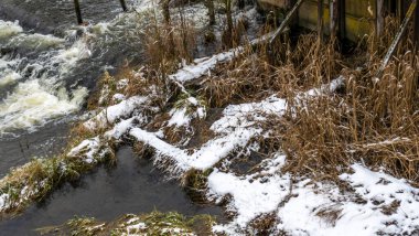 Bir yaya köprüsünün altındaki kış nehrinde kaynar su. Soyut arkaplan. Mesaj için yer var. Doğa kavramları.