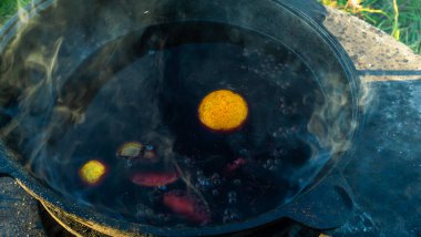 Sıcak sıcak şaraplı kazanlar. Sıcak şarap sokaktaki eski bir kazanda pişirilir. Açık ateşte yemek pişirmek. Yakın plan. Neşeli alkol içeceği..