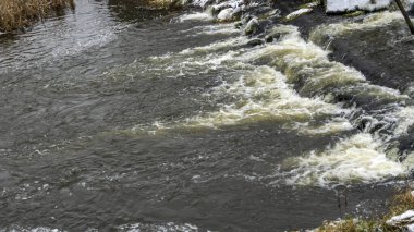Bir yaya köprüsünün altındaki kış nehrinde kaynar su. Soyut arkaplan. Mesaj için yer var. Doğa kavramları.