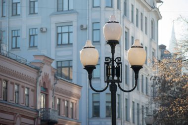 Moskova 'da yaya caddesindeki eski sokak lambalarından biri - Arbat Caddesi - mavi ve sessiz pembe tonlarda eski güzel mimariye karşı