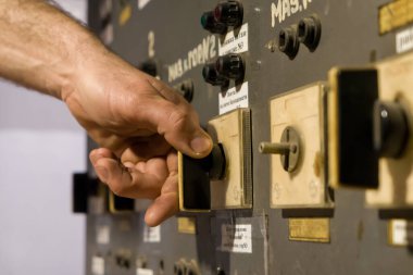 Bir adamın eli eski bir kumanda anahtarını bir bitkiye çeviriyor.