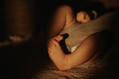 Yeni doğmuş bir bebeğin güneş ışığında kanepede yatarken giydiği mayoyla çekilmiş yakın plan bir fotoğrafı..