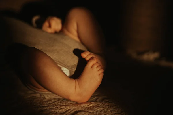 晚上躺在沙发上晒太阳的身穿紧身衣的新生儿腿的特写 — 图库照片
