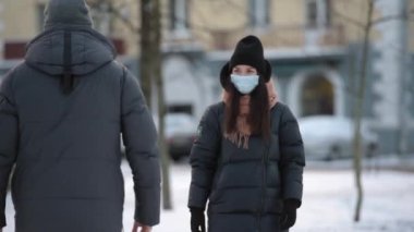 Coronavirus 'un (COVID-19) yayılmasını önlemek için dirsek seği selamı. Kışın tıbbi maskeli bir adam ve kadın sokakta karşılaşır. Sarılmak ya da tokalaşmak yerine, dirseklerini vururlar..