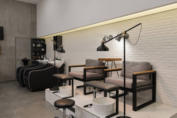 Modern interior of the beauty salon with nail zone with chairs, lamps, sinks and backwashes. 