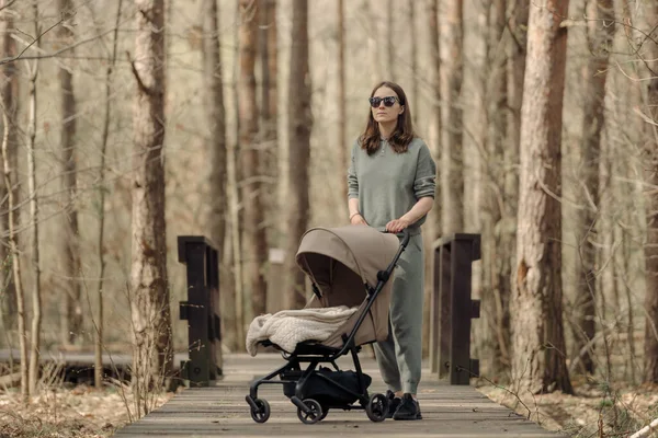 Annem, bebek arabasında uyuyan bir çocukla ahşap bir geçitte yürüyor.