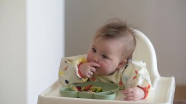 7 aylık beyaz bir kız çıplak elle yemek yiyor..