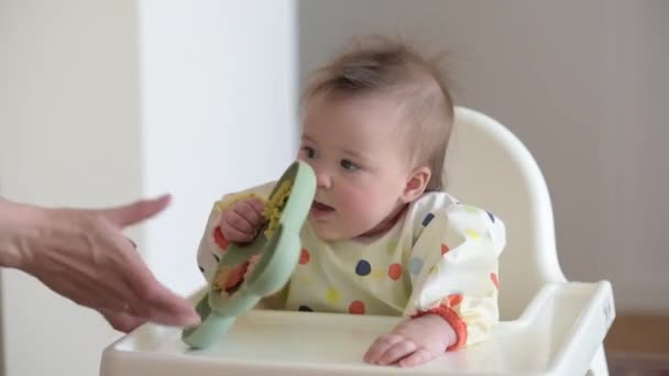 Baby girl is checking the dinner while sitting in a white highchair. — Stockvideo