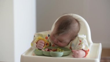 7 aylık beyaz bir kız yiyeceğe çıplak elle dokunuyor. 