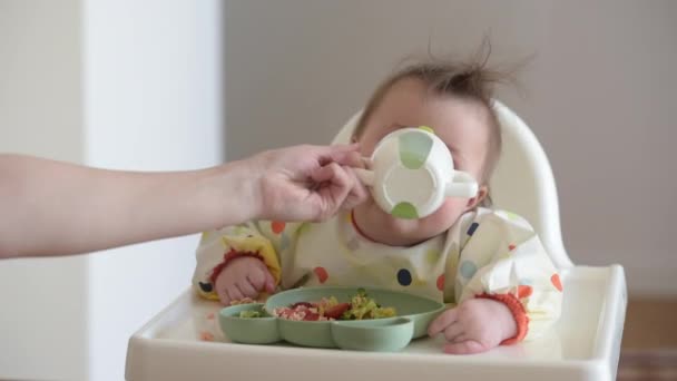 The hand of the mother who is giving water to her infant 7-month daughter. — Stockvideo