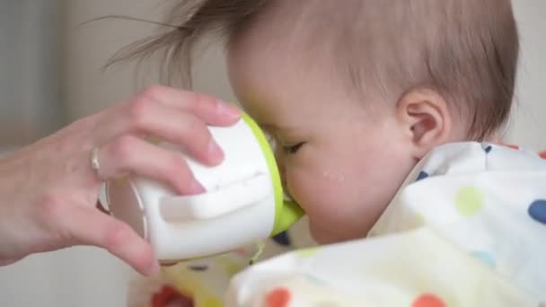 Een kind van 7 maanden dat drinkt uit de beker in de handen van haar moeder. — Stockvideo