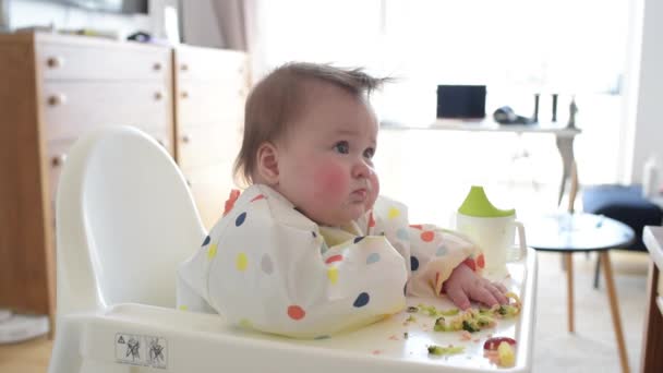 An infant 7-month caucasian girl is eating broccoli with bare hands. — Stockvideo