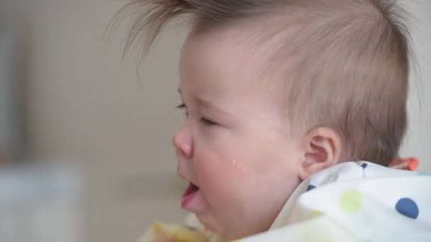A close-up shot of an infant 7-month caucasian girl who is coughing during lunch — ストック動画