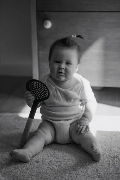 A black and white photo of a 7-month girl is sitting on the carpet — ストック写真