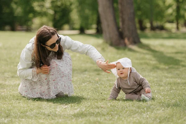 Uma mãe está brincando com sua filha de 7 meses no prado. — Fotografia de Stock